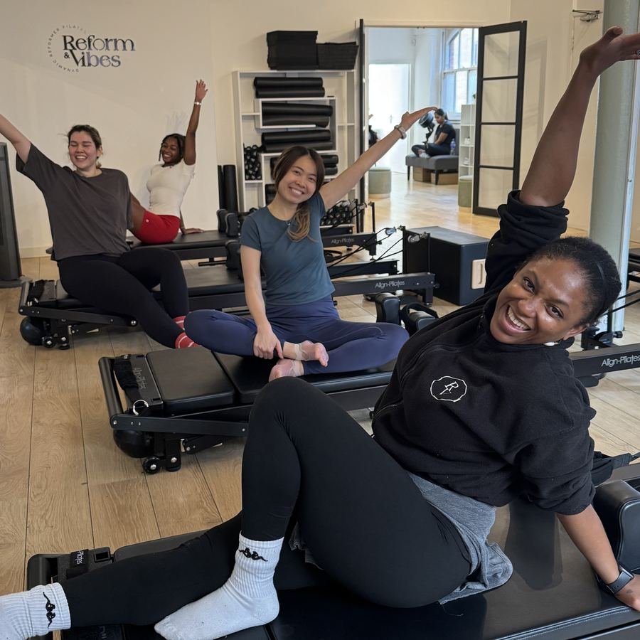 Smiling clients stretching together on the reformers at Reform and Vibes